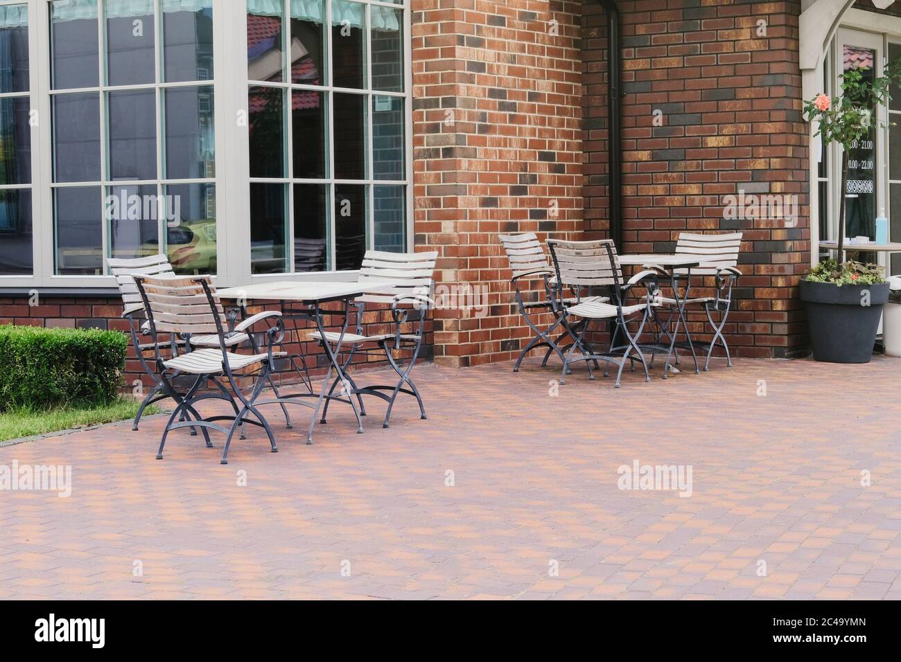 Leere Terrasse im Sommer in Erholung in der Stadt. Weißer Holztisch und Sessel auf der Außenterrasse des Sommercafés. Restaurantbetrieb erwartet Sie Stockfoto