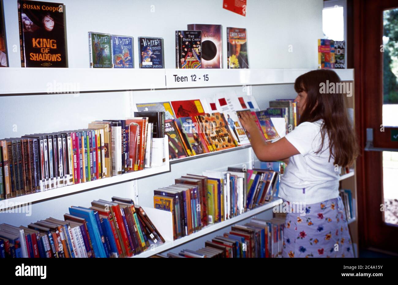 Kind in der Bibliothek Bücher durchsuchen Cheam Surrey England Stockfoto