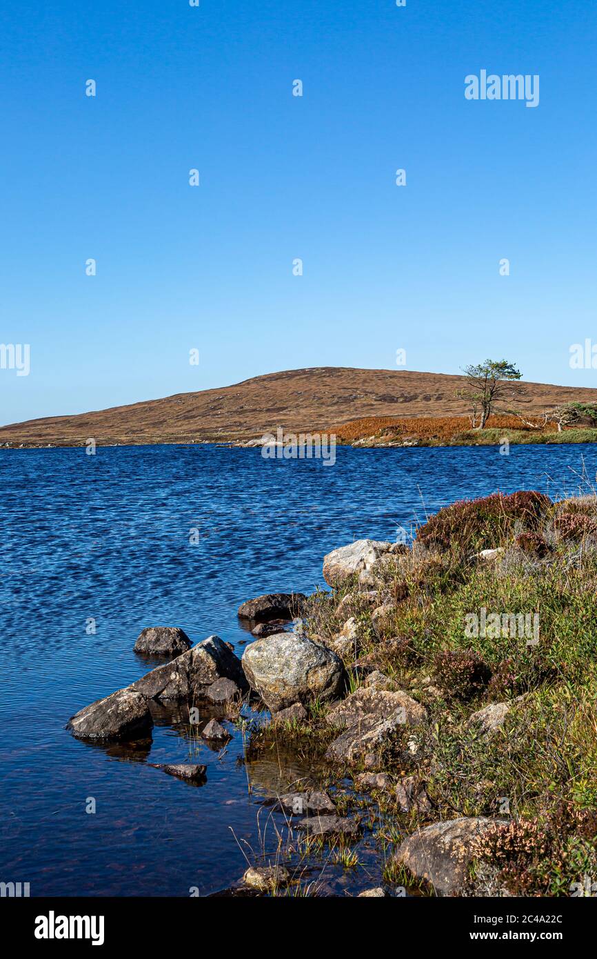 Blick über Loch Druidibeg auf der hebridischen Insel South Uist, mit einem blauen Himmel über dem Meer Stockfoto