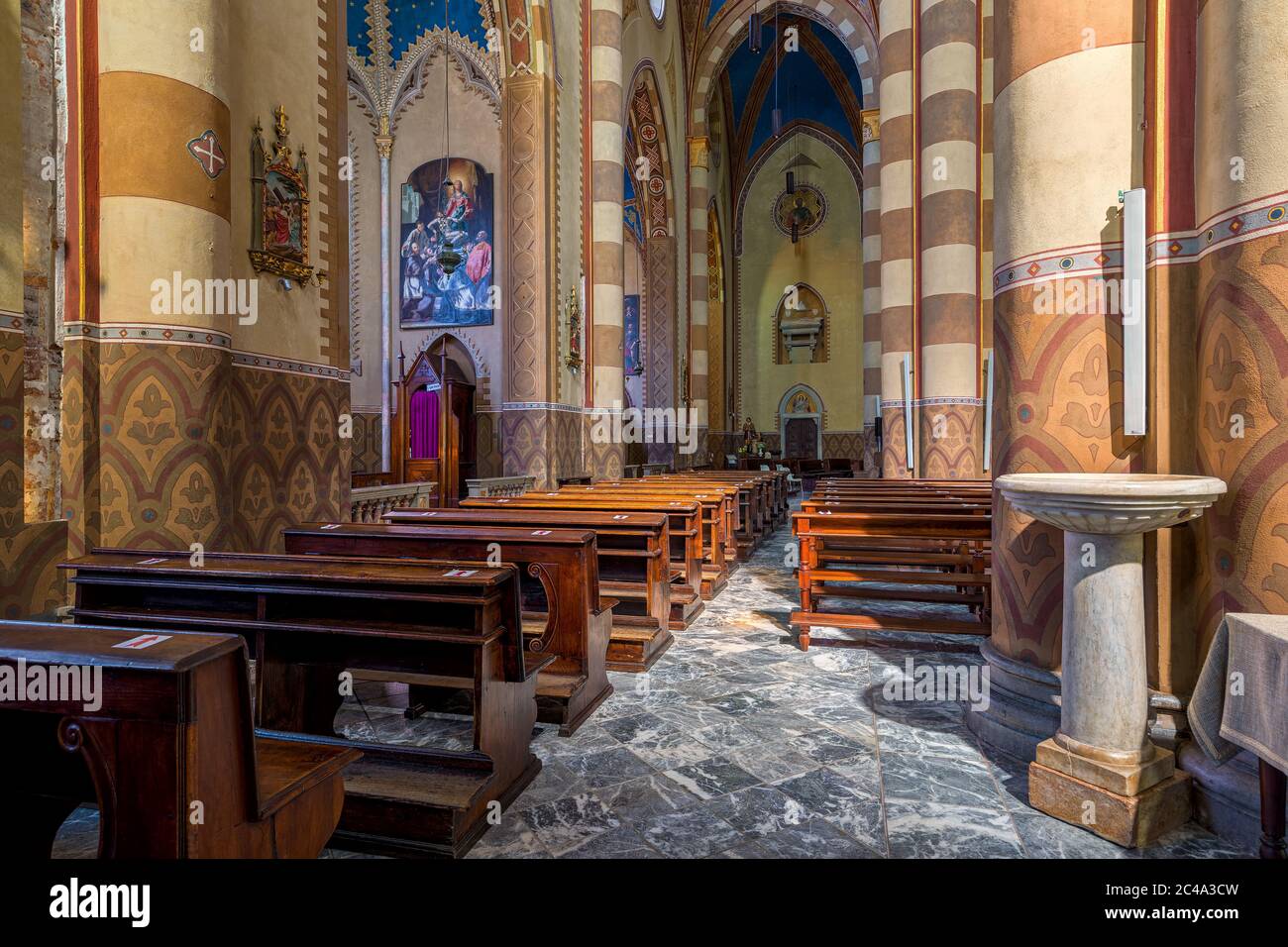 Holzbänke, Seitenschiff und Säulen im Inneren von San Lorenzo - einer römisch-katholischen Kathedrale alias Duomo in Alba, Italien. Stockfoto