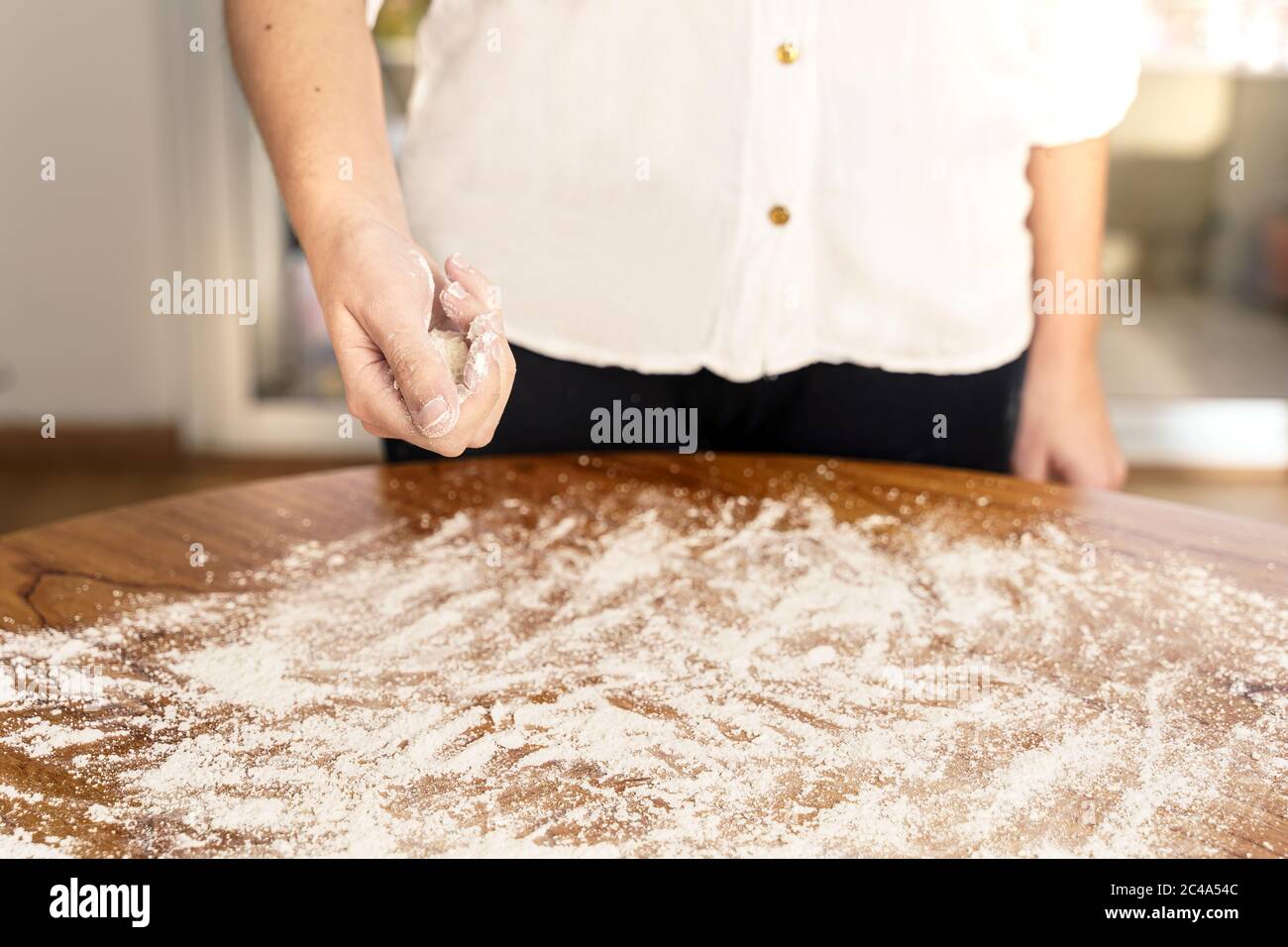 Hände einer Frau, die Mehl auf den Tisch streut Stockfoto