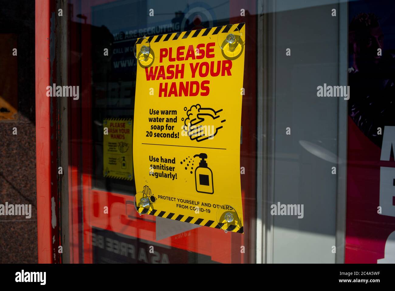 Bitte waschen Sie sich die Hände Zeichen auf einem Schaufenster von Bet Fred Wettshop in Portswood Southampton. Schild sind auf Geschäften aufgrund von Coronavirus Pandemie sichtbar Stockfoto