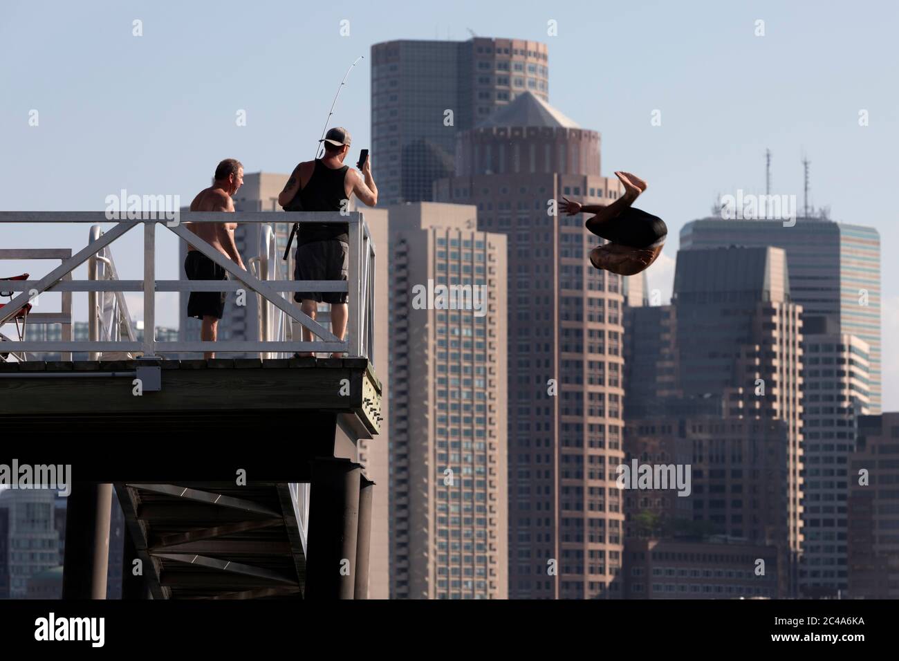 Mann springt von einem Pier, Boston Hafen Skyline, Boston, Massachusetts Stockfoto