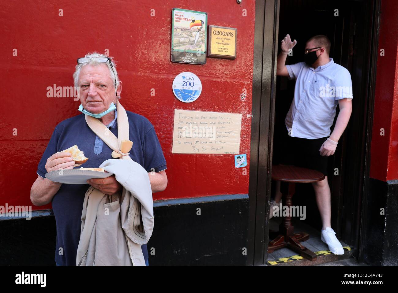Der irische Politiker Nicky Kelly isst sein kostenloses geröstetes Sandwich, das ihm der Barkeeper Daniel Smith (rechts) in der Grogans Castle Lounge im Stadtzentrum von Dublin gab. Die Kneipe kündigte in den sozialen Medien an, dass sie heute Nachmittag einige ihrer geliebten Toasties kostenlos verteilen würden. Pubs und Hotelbars, die als Restaurants dienen, können am Montag, den 29. Juni, im Einklang mit der Phase 3 der Lockerung der COVID-19-Beschränkungen der Regierung, für die Öffentlichkeit wieder geöffnet werden. Stockfoto