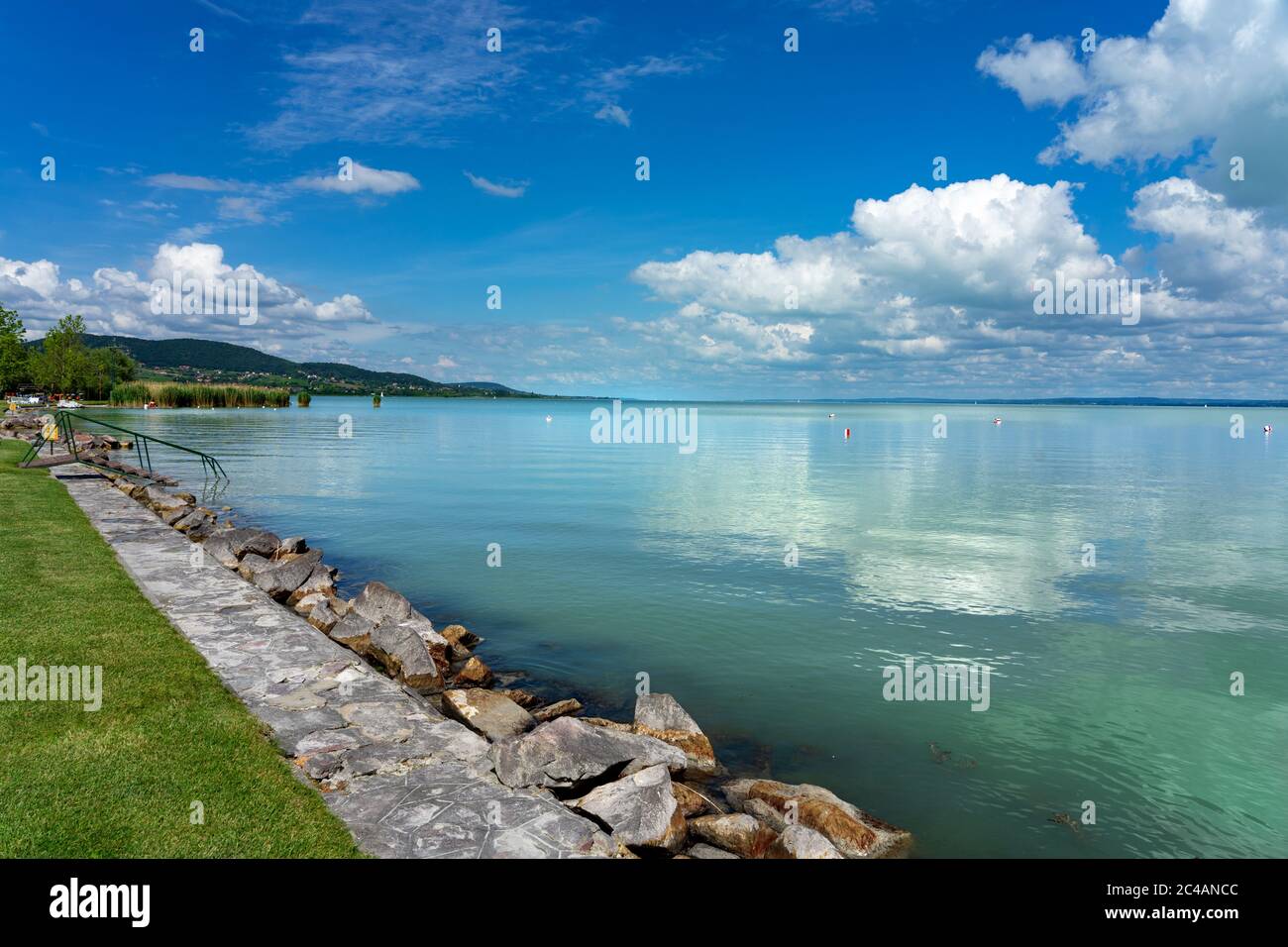 Einfaches Bild über den Plattensee in Ungarn von Badacsony Strand mit blauem Himmel und Wolkenbewölkung und Treppen ins Wasser. Stockfoto