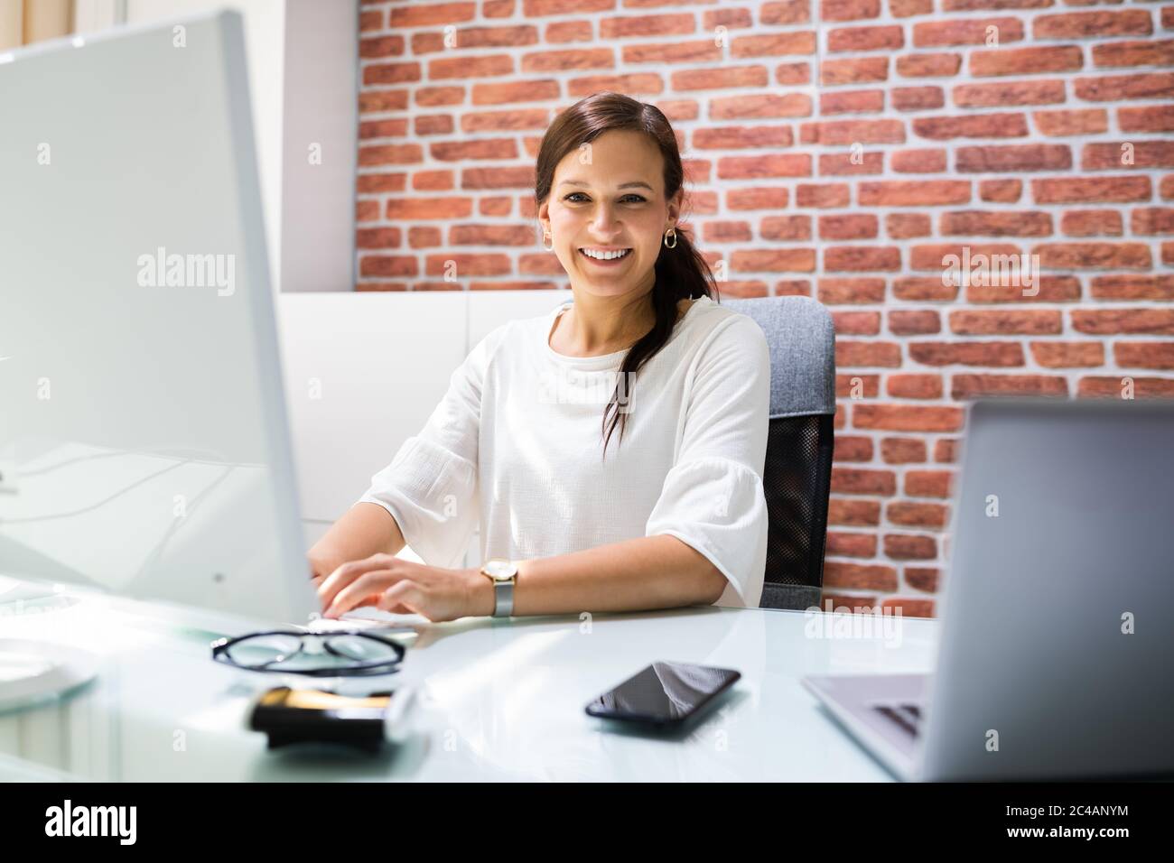 Glückliche Geschäftsfrau Am Büroschreibtisch, Die Computertechnologie Benutzt Stockfoto