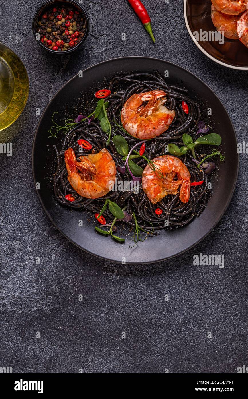 Italienische Pasta schwarze Spaghetti mit Garnelen und Microgreens, Draufsicht. Stockfoto