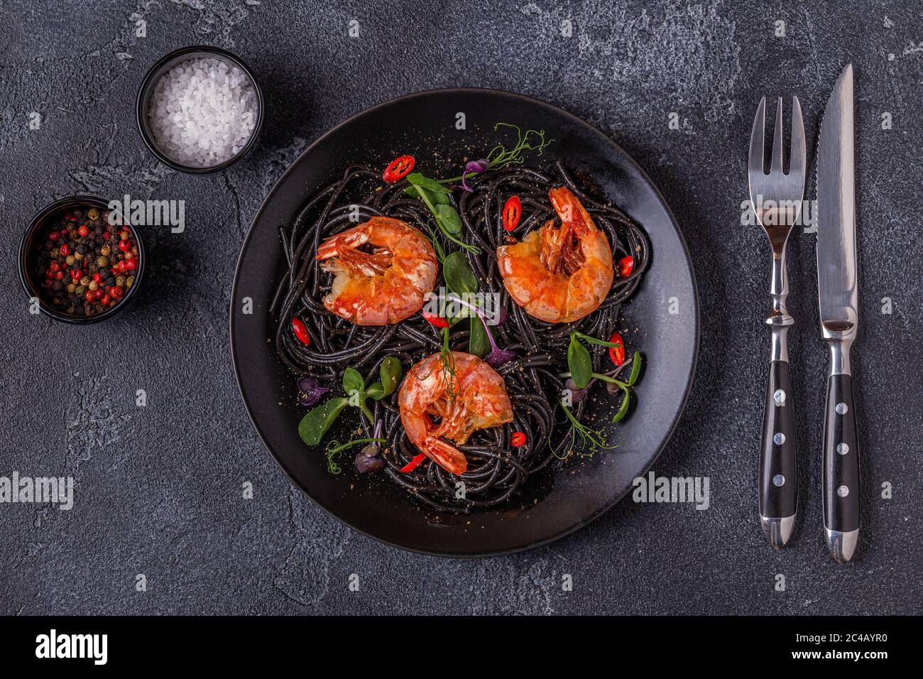 Italienische Pasta schwarze Spaghetti mit Garnelen und Microgreens, Draufsicht. Stockfoto
