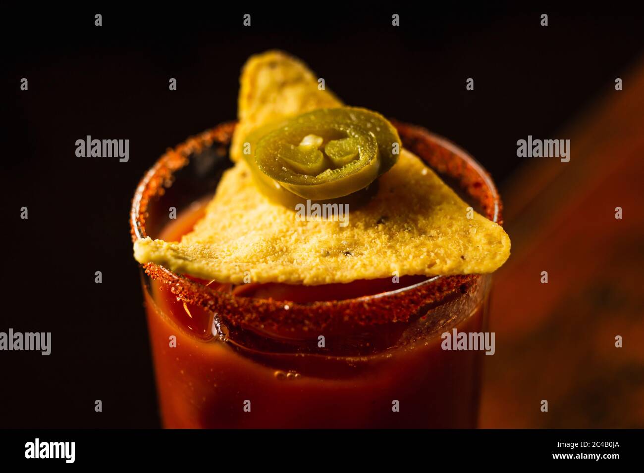 Bloody mary Cocktail garniert mit Nachos und Jalapeno Pfeffer, horizontale Makro-Aufnahme Stockfoto
