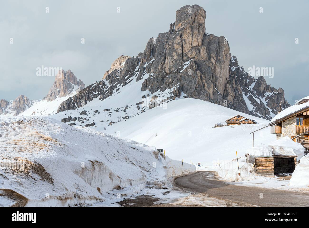 Leere kurvenreiche Straße, die an einem bewölkten Tag in einer winterlichen Bergkulisse in den Dolomiten von Schnee befreit ist Stockfoto