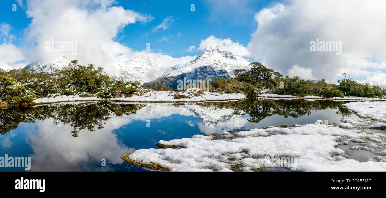 Kleiner Bergsee mit Spiegelung, Blick auf wolkenbedeckte Berge, Schnee auf dem Gipfel des Key Summit, Mt. Christina, Fiordland National Park, West Stockfoto