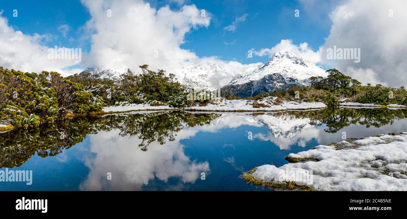 Kleiner Bergsee mit Spiegelung, Blick auf wolkenbedeckte Berge, Schnee auf dem Gipfel des Key Summit, Mt. Christina, Fiordland National Park, West Stockfoto