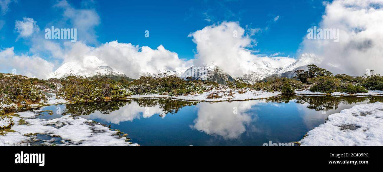 Kleiner Bergsee mit Spiegelung, Blick auf wolkenbedeckte Berge, Schnee auf dem Gipfel des Key Summit, Mt. Christina, Fiordland National Park, West Stockfoto