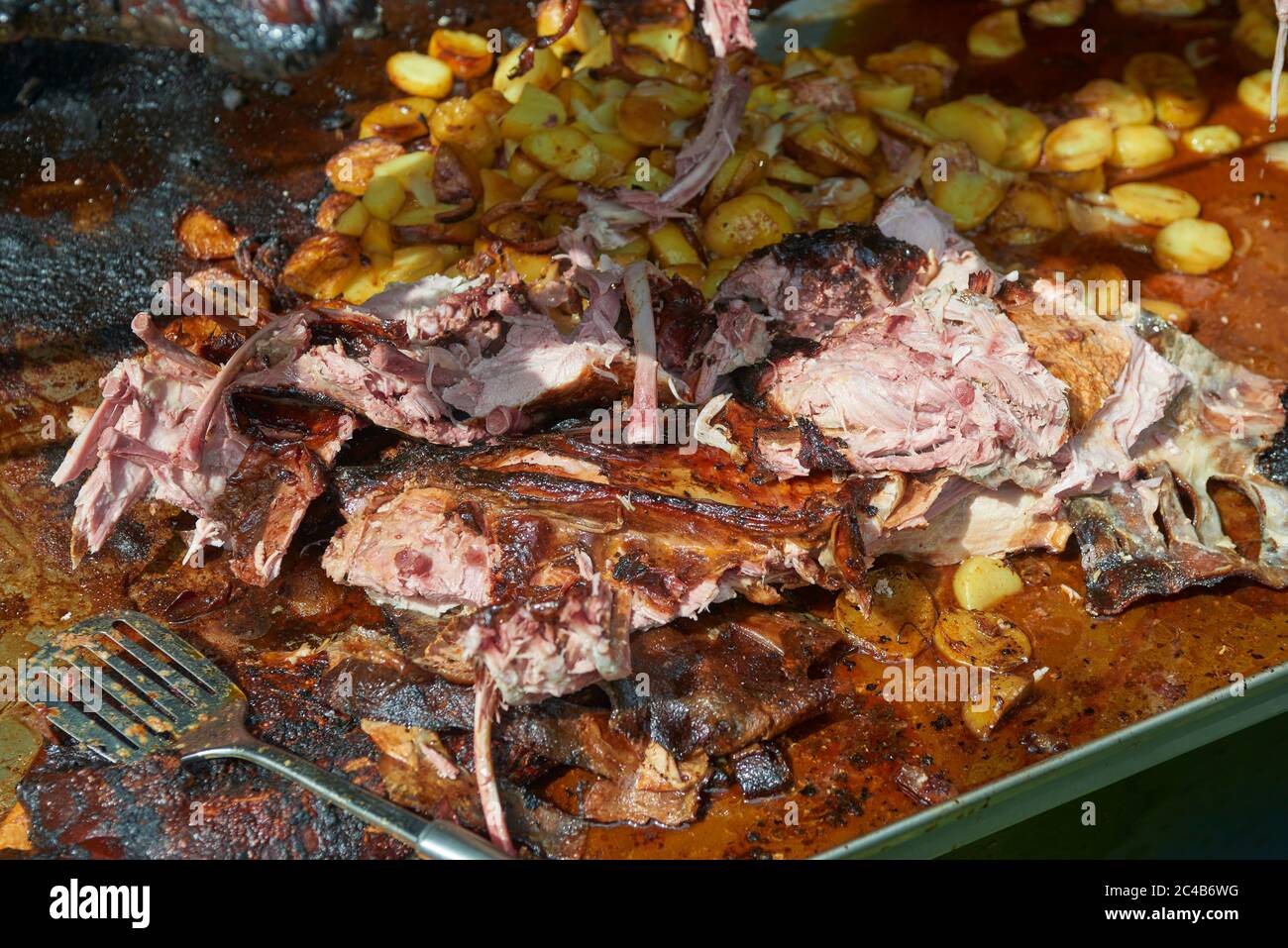 Chef Hände Schneiden ganze gegrillte Schweinefleisch für Steaks mit Messer. Vom Schwein gegrillte traditionelle Kohle und Feuer. Das kleine Schwein wird ganz auf einem offenen Feuer geröstet. Stockfoto