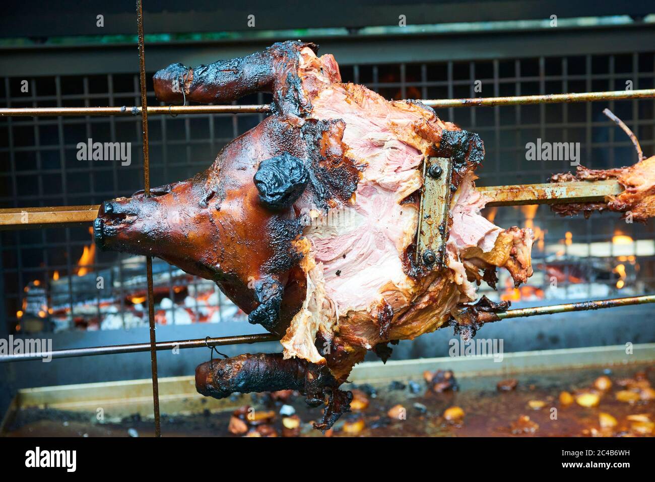 Chef Hände Schneiden ganze gegrillte Schweinefleisch für Steaks mit Messer. Vom Schwein gegrillte traditionelle Kohle und Feuer. Das kleine Schwein wird ganz auf einem offenen Feuer geröstet. Stockfoto