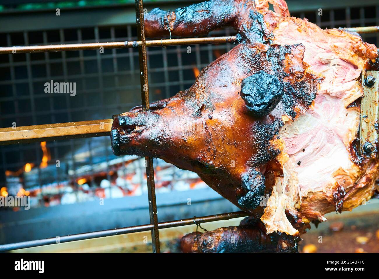 Chef Hände Schneiden ganze gegrillte Schweinefleisch für Steaks mit Messer. Vom Schwein gegrillte traditionelle Kohle und Feuer. Das kleine Schwein wird ganz auf einem offenen Feuer geröstet. Stockfoto