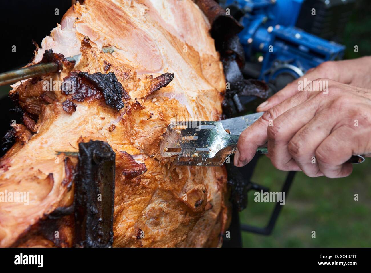 Chef Hände Schneiden ganze gegrillte Schweinefleisch für Steaks mit Messer. Vom Schwein gegrillte traditionelle Kohle und Feuer. Das kleine Schwein wird ganz auf einem offenen Feuer geröstet. Stockfoto