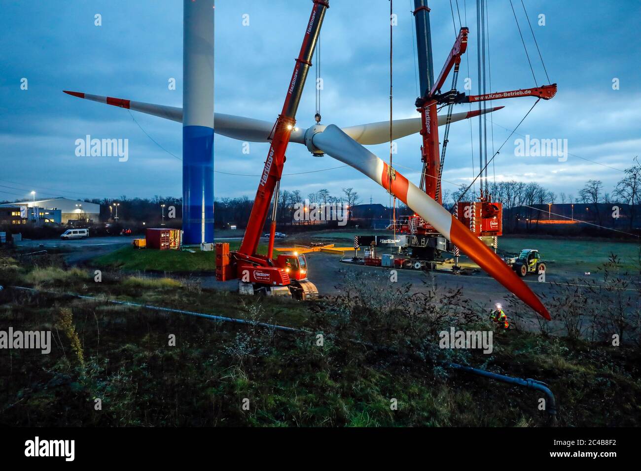 Montage eines Windkraftwerks, Krane heben Rotorring mit Rotorblättern in der Dämmerung, Bottrop, Ruhrgebiet, Nordrhein-Westfalen, Deutschland Stockfoto