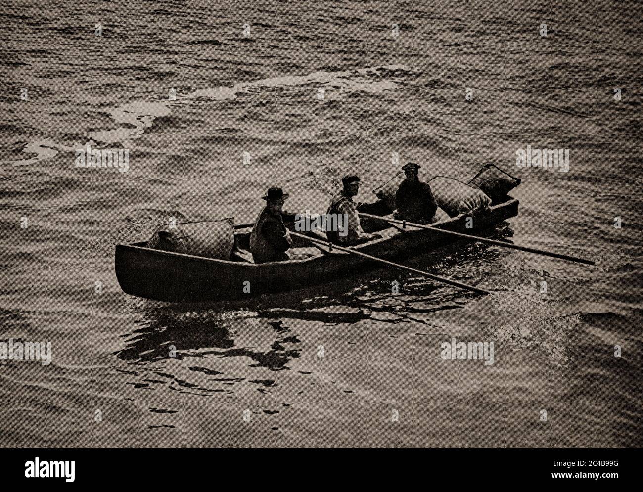 Eine Ansicht der Aran Islanders, die Anfang der 20er Jahre eine Currach rudern, um den zweimal wöchentlich stattfindenden Dampfer zu treffen. County Galway. Ursprünglich fotografiert von A. W. Cutler (1875-1935) für 'Ireland: The Rock Whence I was Hewn', eine National Geographic Magazine-Spielfilm vom März 1927. Stockfoto