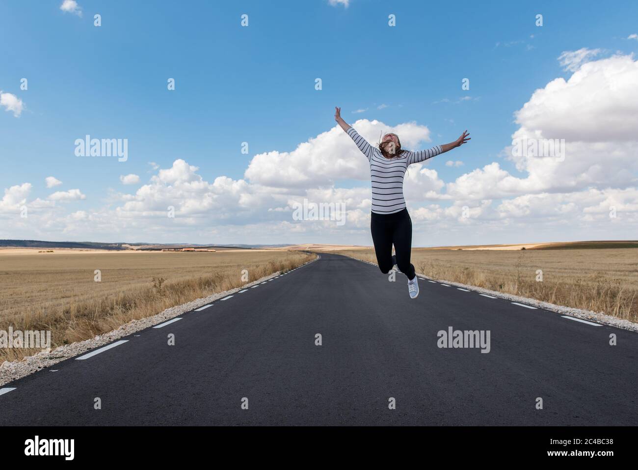 Junge Frau springt auf der Straße auf nirgendwo Stockfoto
