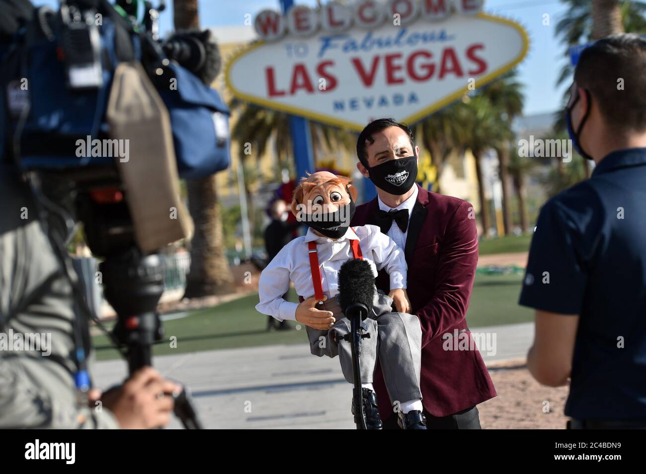 Las Vegas, Nevada, USA. Juni 2020. Der Bauchredner Romeo Le Formidable und sein Dummy Luigi sprechen mit den Medien, nachdem er an einer Modenschau vor dem Schild Welcome to Fabulous Las Vegas auf dem Las Vegas Strip teilgenommen hat, um die Maskenmaskenkampagne 'Mask up for Nevada' von Experience Strategy Associates zu starten Inmitten der Ausbreitung des Coronavirus am 25. Juni 2020 in Las Vegas, Nevada. Am Mittwoch, Nevada Gov. Steve Sisolak unterzeichnete eine Richtlinie, die Menschen verpflichtet, Gesichtsbezüge an öffentlichen Orten im ganzen Staat ab Juni 26 als Reaktion auf eine vier-Wochen-Aufwärtstrend tragen Stockfoto