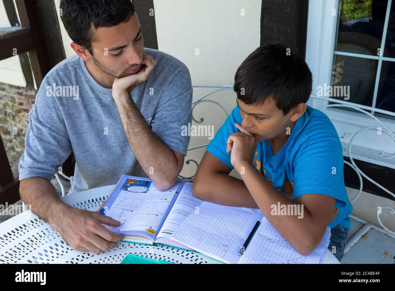 Junger Mann hilft seinem jüngeren Bruder bei den Hausaufgaben Stockfoto