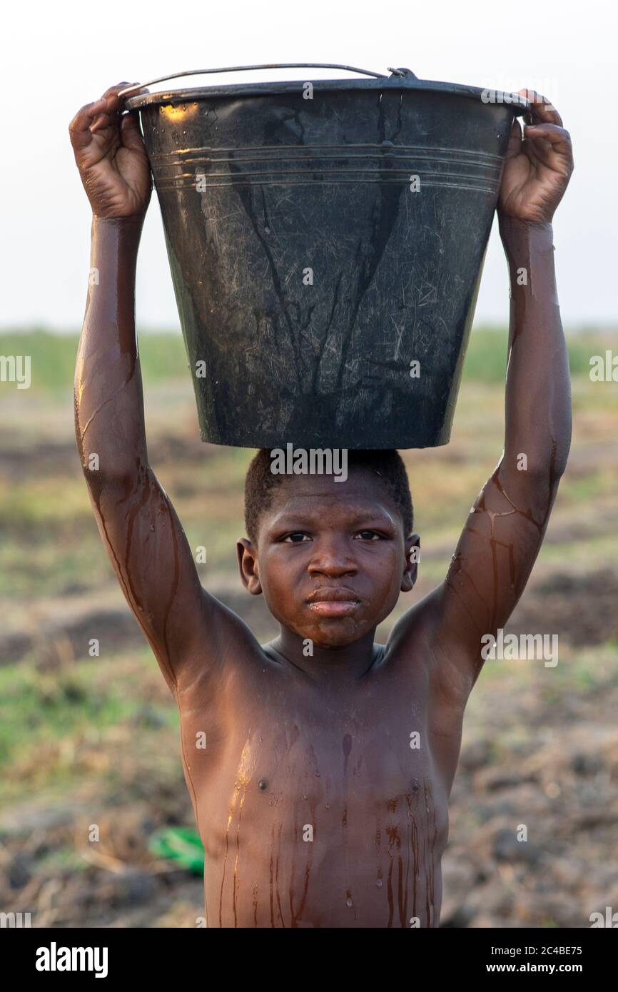 Junge wässern ein Feld in Karsome, togo Stockfoto