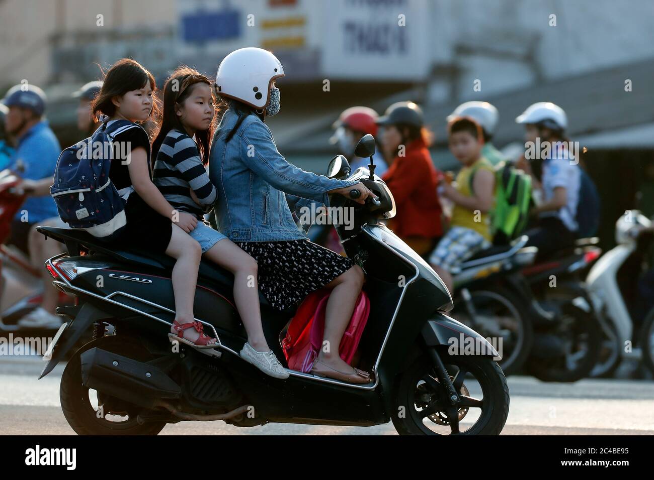 Mutter und Kinder reiten motorbile auf dem Weg zur Schule Stockfoto