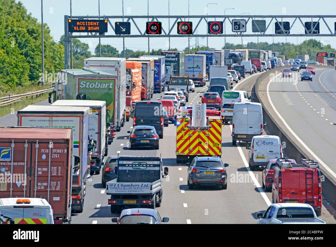 Autobahnraststätte Stau & Feuerwehrmotor auf Rettungsdienst rufen Unfallort in der Nähe von Brentwood zu erreichen, wie auf m25 Gantry Road Sign UK gezeigt Stockfoto