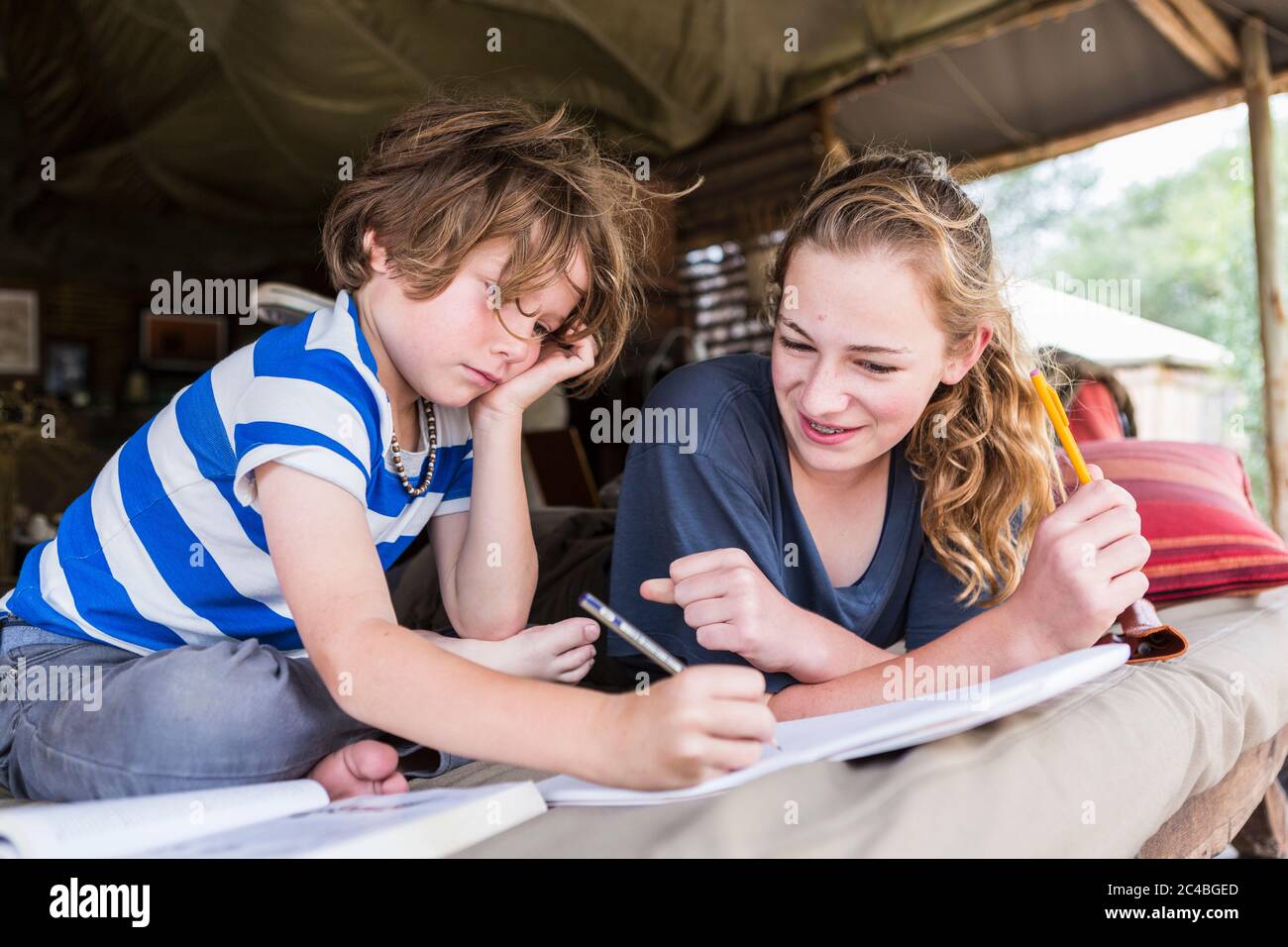 Bruder und Schwester machen gemeinsam Hausaufgaben in einem Zeltlager in Botswana Stockfoto