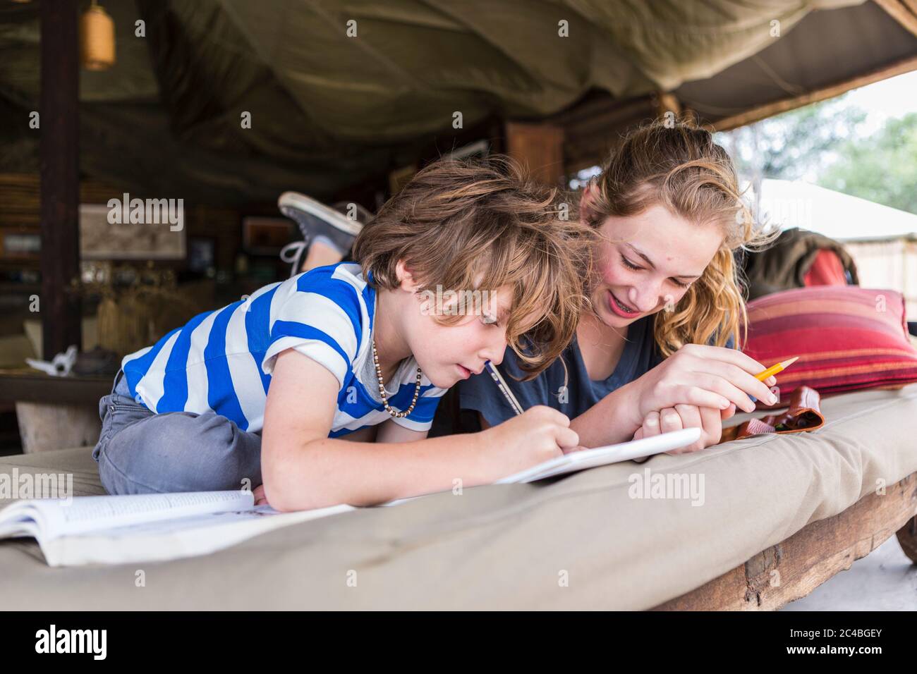 Bruder und Schwester machen gemeinsam Hausaufgaben in einem Zeltlager in Botswana Stockfoto