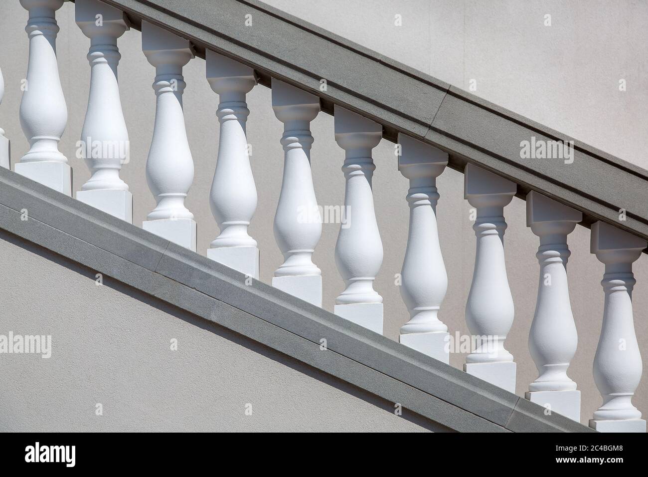 Weiße Geländer der grauen Steintreppe, Nahaufnahme von Details der Architektur, die von der Sonne beleuchtet werden. Stockfoto