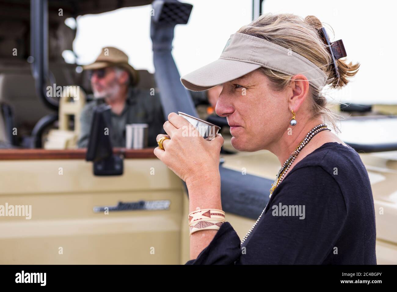 Erwachsene Frau schlürft Kaffee auf Safari, Nxai Pan, Botswana Stockfoto