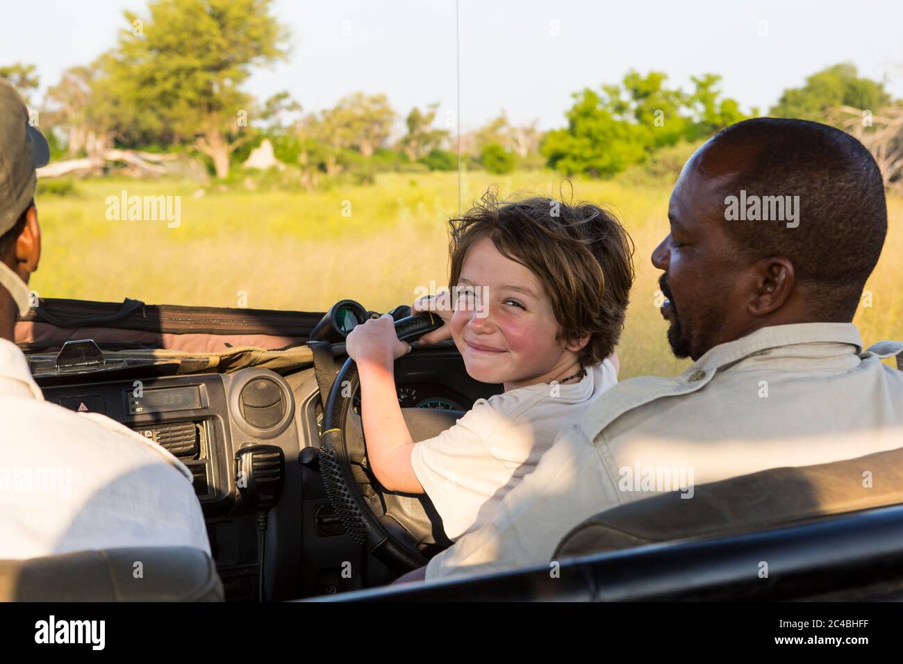 Lächelnd 6 Jahre alt Junge Lenkung Safari Fahrzeug, Botswana Stockfoto