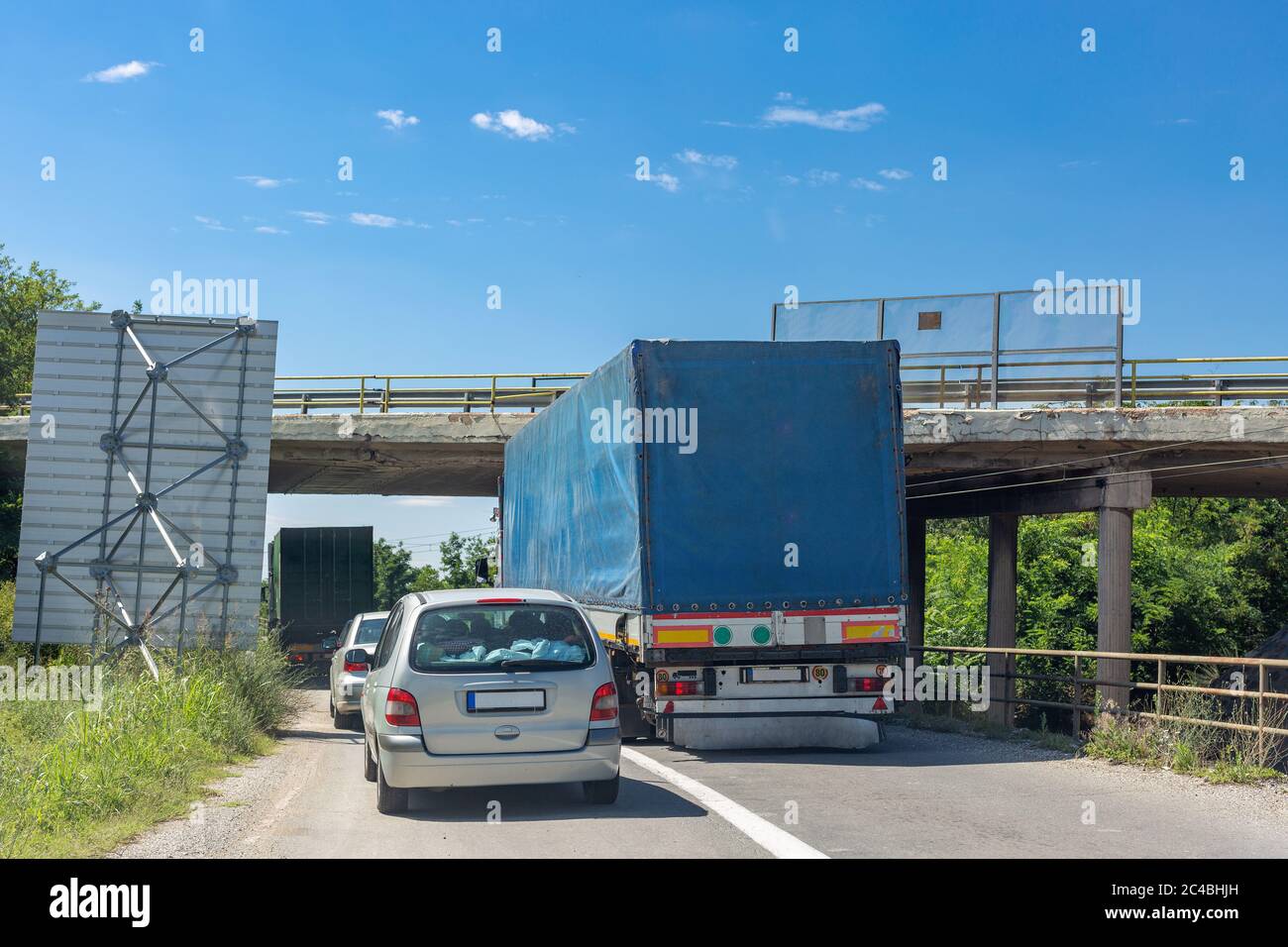 Blauer Weg, der versucht, unter der erhöhten Straße zu passieren. Fahrzeug kollidiert mit der Brücke Stockfoto