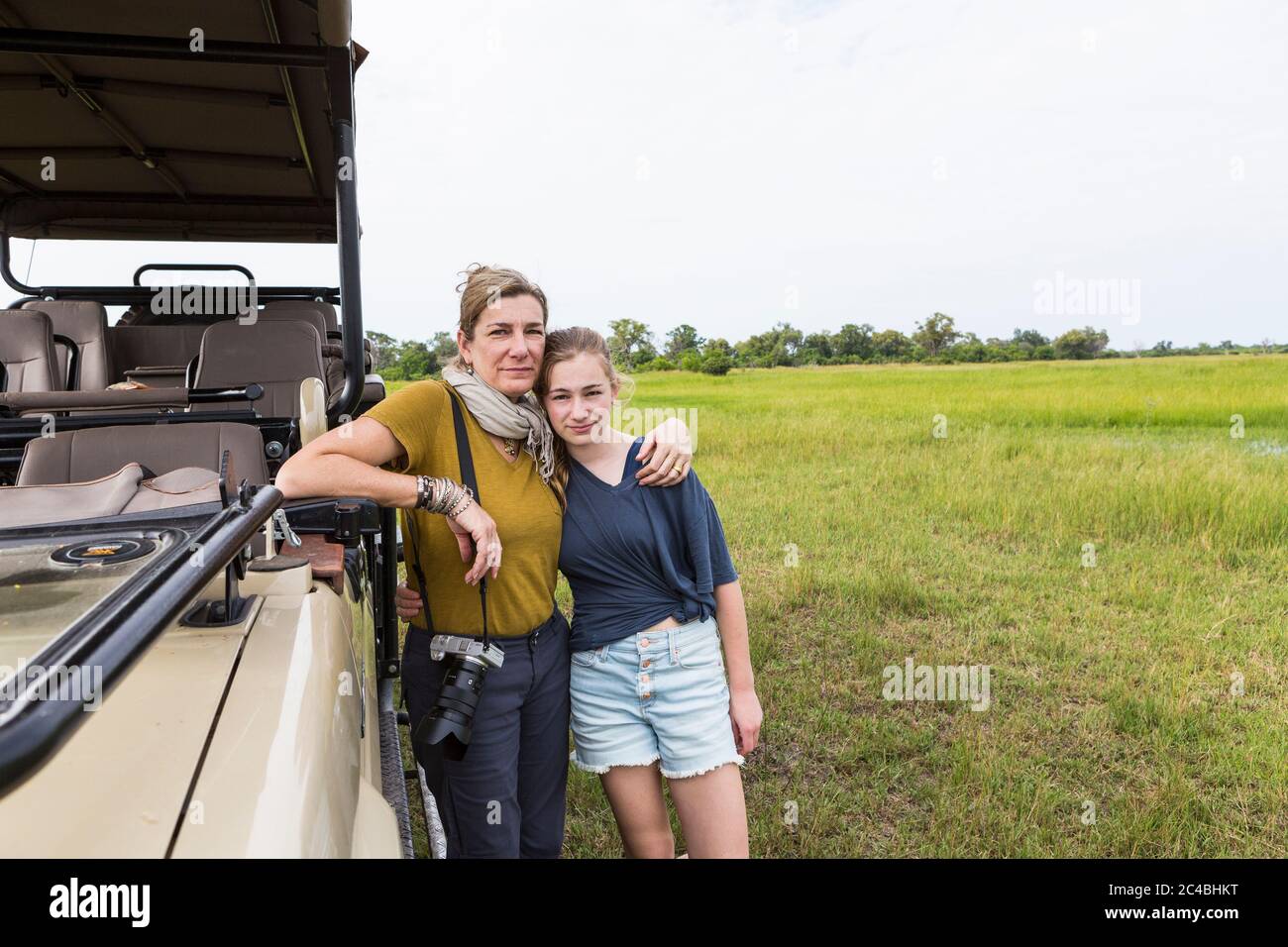 Mutter fotografiert mit Teenager-Tochter in der Nähe von Safari-Fahrzeug, Botswana Stockfoto