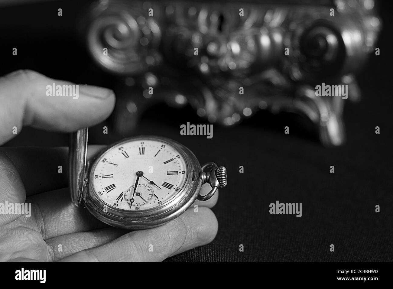 Eine Hand mit einer alten Taschenuhr in schwarz und weiß Stockfoto