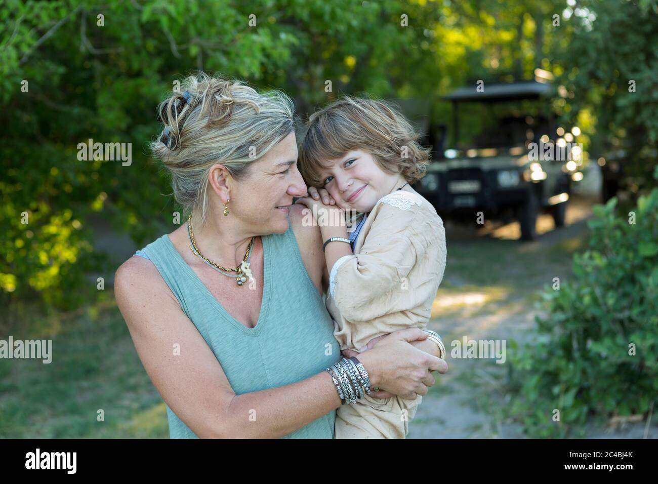 Eine Frau, Mutter, die ihren fünfjährigen Sohn in einem Wildreservelager trägt. Stockfoto