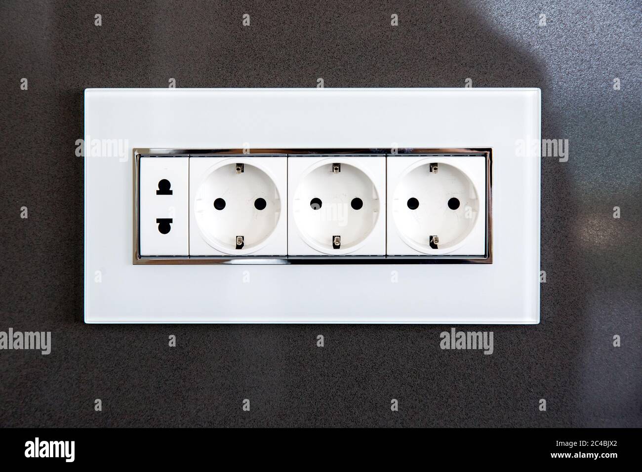 Steckdose mit Steckern für Standard-Stecker Typ A und Standard-Stecker Typ F  in weißem Kunststoffgehäuse an einer dunkelgrauen, glänzenden Steinwand  Stockfotografie - Alamy