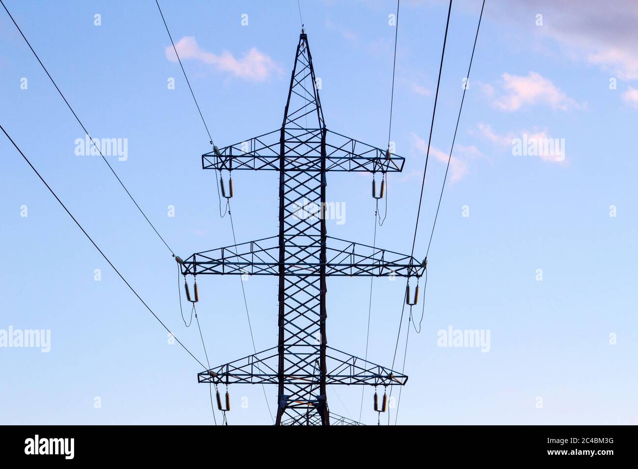 Hochspannungsleitungen in der Mitte eines Feldes bei Sonnenuntergang. Industrialisierung. Elektrifizierung. Stromversorgung. Stockfoto