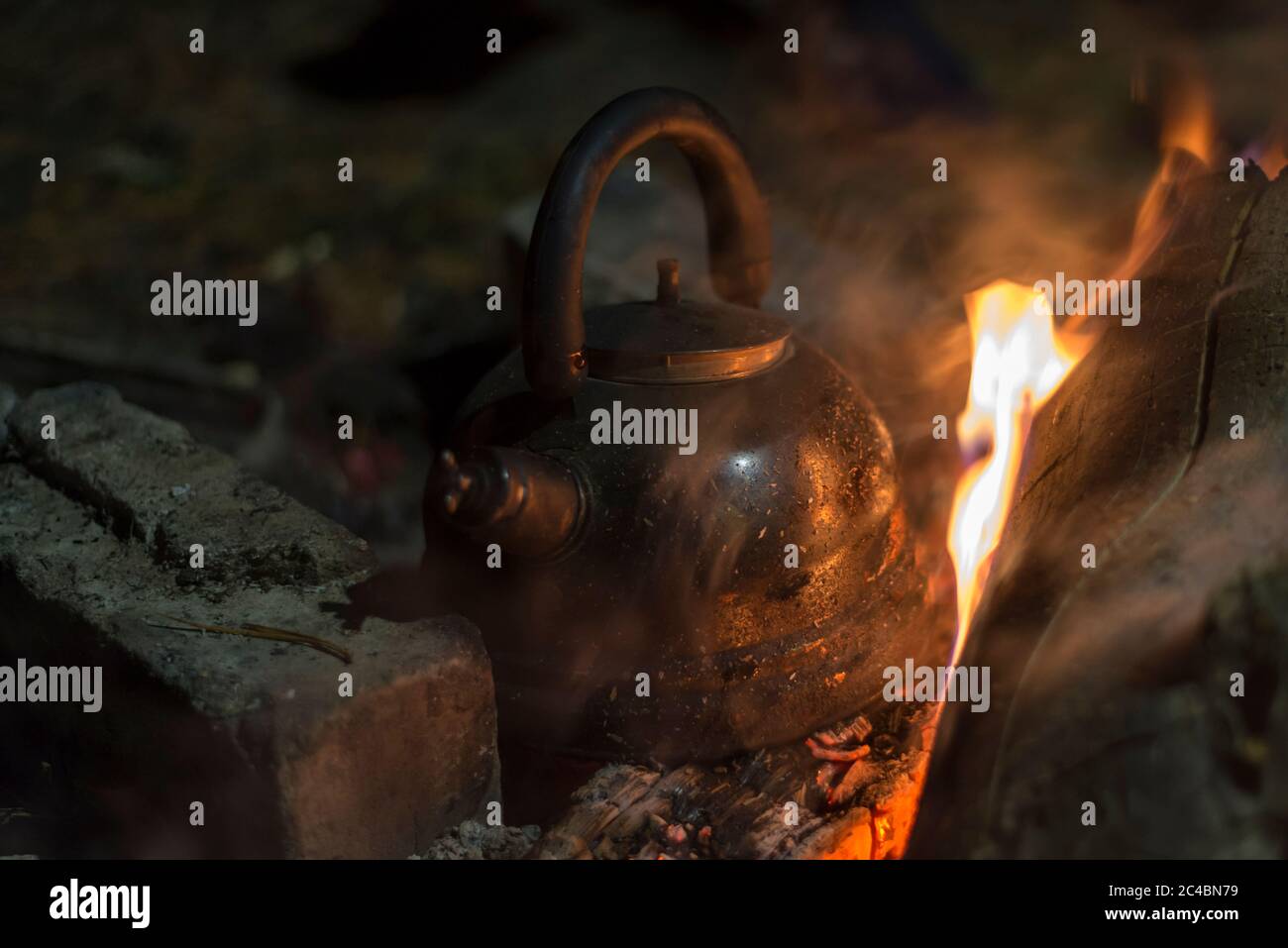 Der Wasserkocher wird nachts an einem hellen Feuer im Freien erhitzt Stockfoto