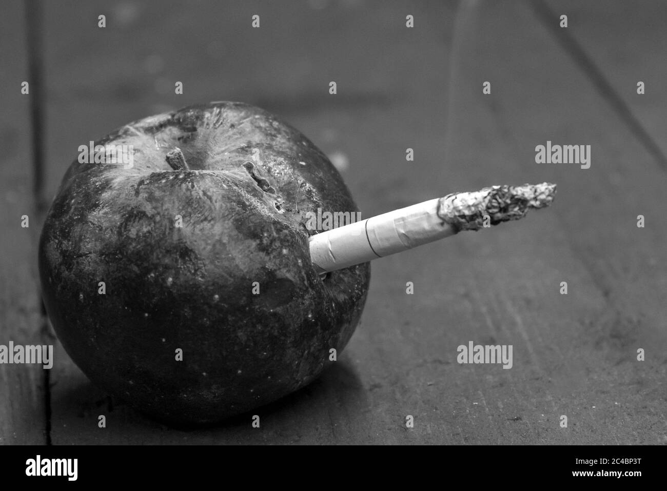 Zigarette in einem faulen getrockneten Apfel, das Konzept der Schaden des Rauchens, schwarz-weiß Foto eingefügt Stockfoto