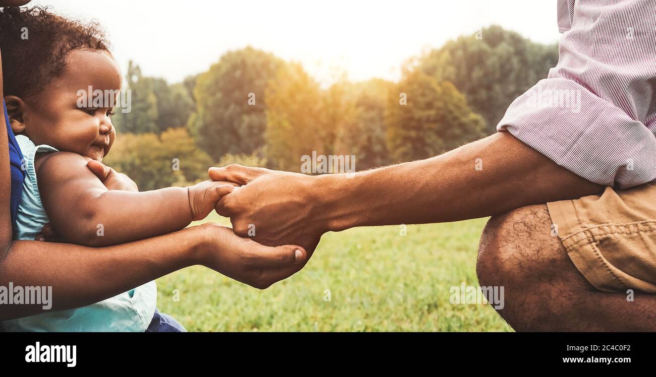 Glückliche afrikanische Familie, die gemeinsam im öffentlichen Park Spaß hat - Schwarzer Vater und Mutter halten Hand mit ihrer Tochter Stockfoto