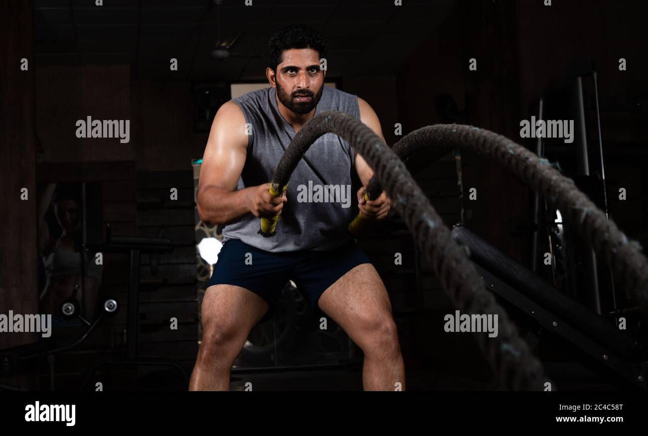 Asiatische indische Mann tun Übung mit Kampf Seil in Turnhalle Stockfoto