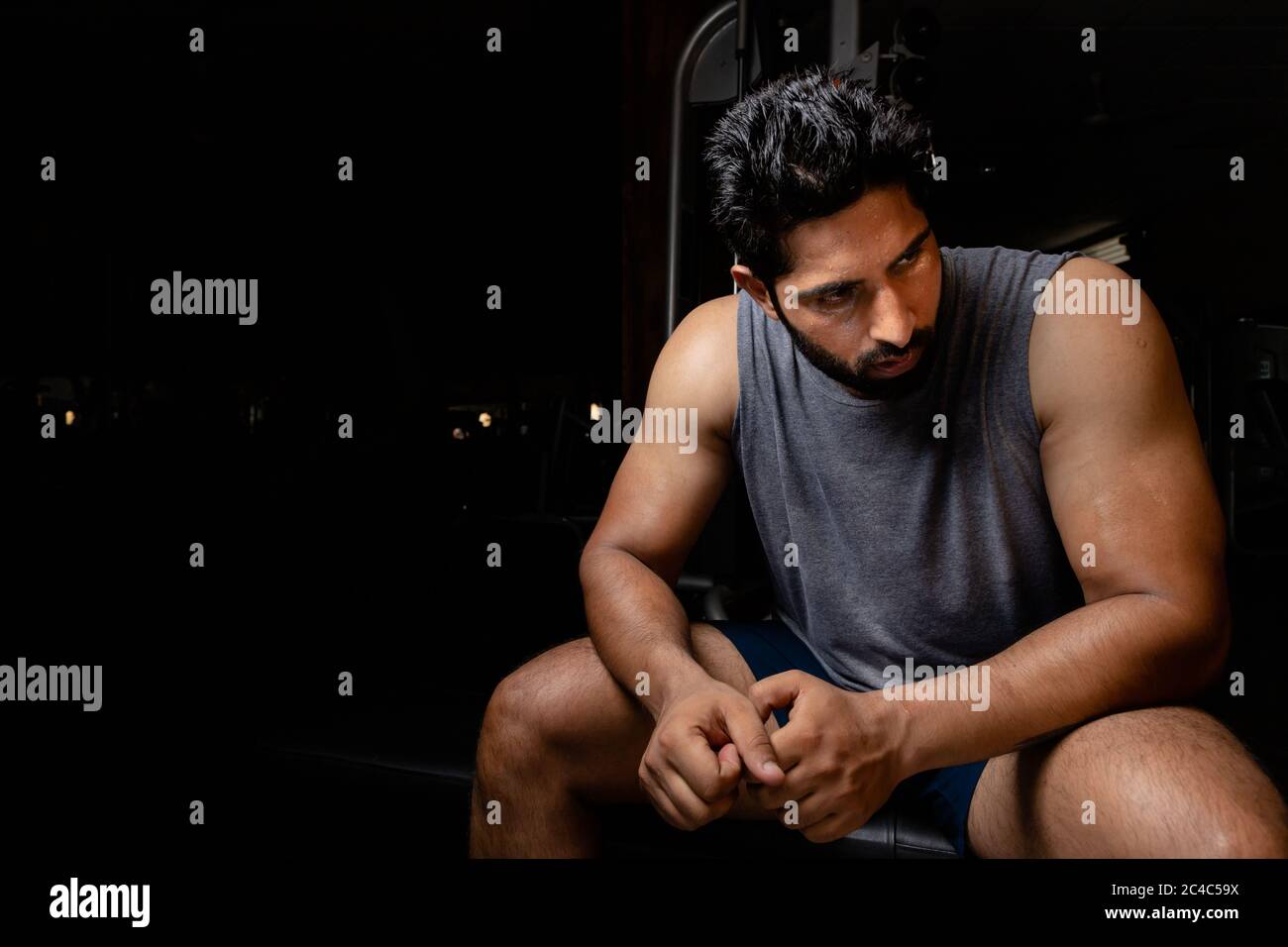 Asiatisch indisch erschöpft müde Mann sitzen auf Tisch nach dem Workout im Fitnessstudio Stockfoto