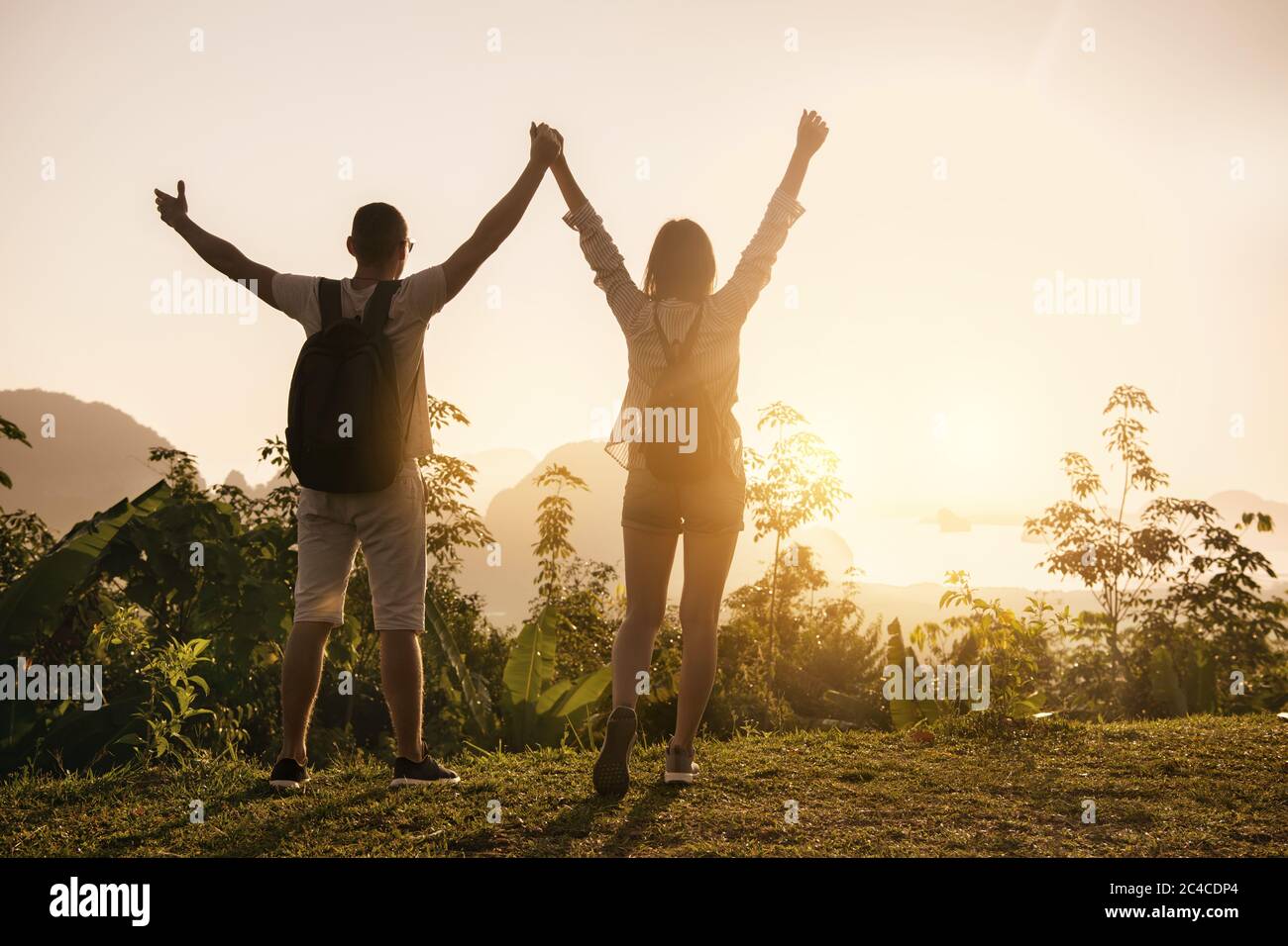 Zwei glückliche Touristen stehen mit erhobenem Arm am Aussichtspunkt und genießen den Sonnenaufgang Stockfoto