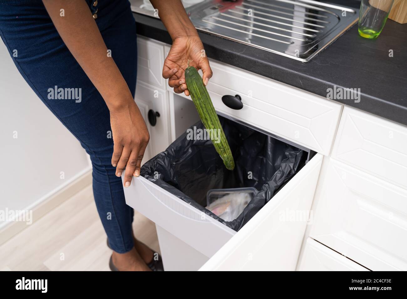 Afrikanische Frau Wirft Weg Essen In Mülltaufen Stockfoto