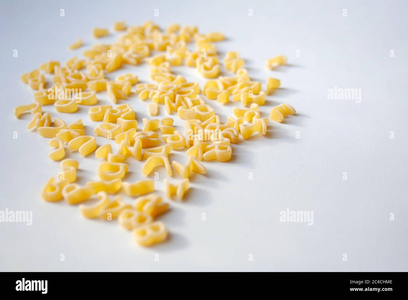 Rohe Nudelbuchstaben des Alphabets gemischt in Haufen auf weißem Hintergrund Stockfoto