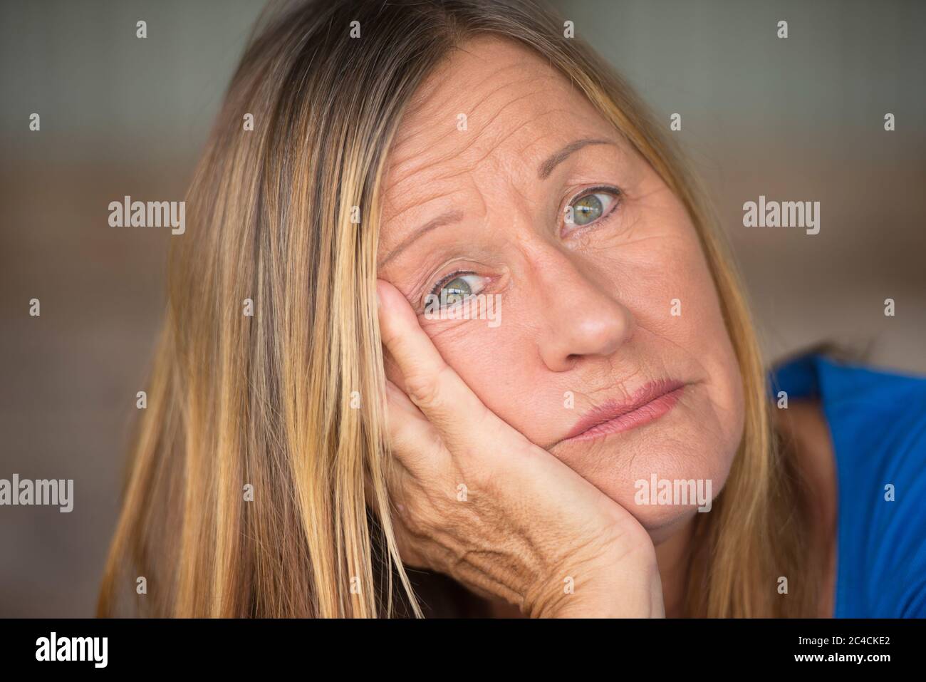 Portrait Attraktive reife Frau mit gelangweilter, gestresster, einsamer, depressiver und trauriger Mimik, verschwommener Hintergrund. Stockfoto