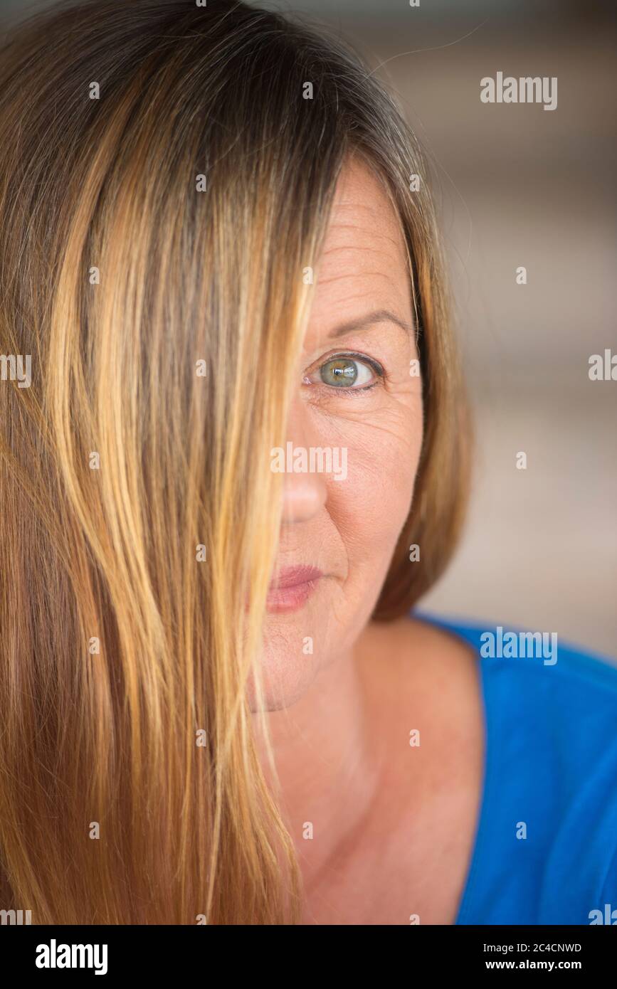 Portrait Attraktive Frau mit brünetten Haaren bedeckt Halbgesicht, ein Auge zuversichtlich geheimnisvolle nach oben schauen, verschwommener Hintergrund. Stockfoto